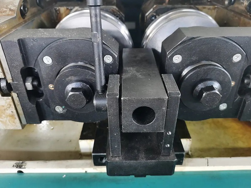 close up of a metal machine part with rollers and a central mechanism