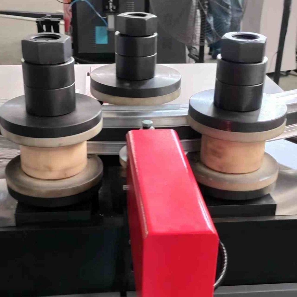 Máquina dobladora de perfiles de aluminio con sensor de posicionamiento de precisión y mordazas de sujeción.