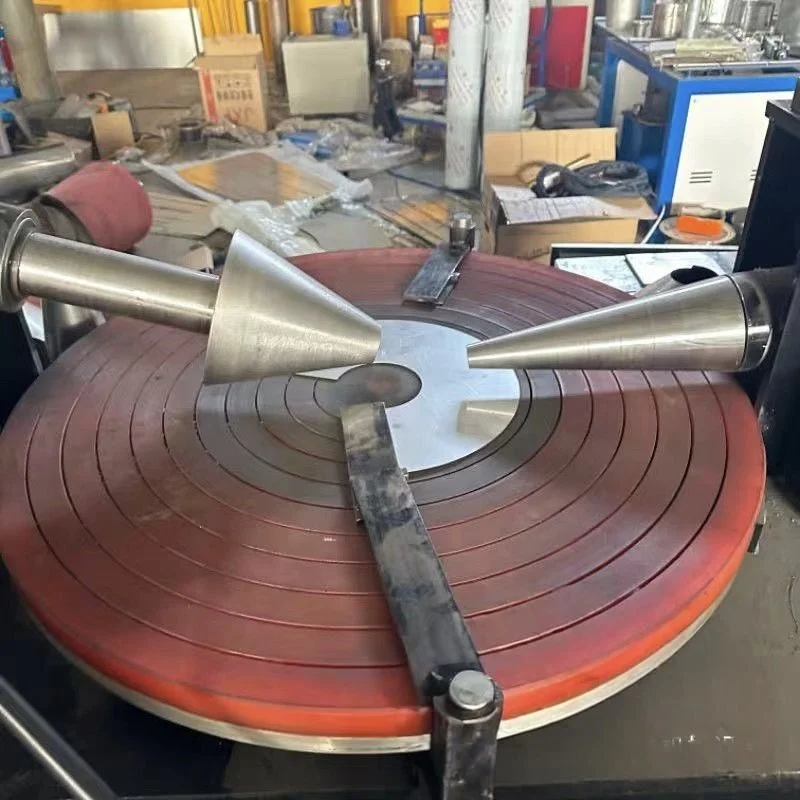 Крупный план рабочего стола конусопрокатного станка дискового типа в заводском цехе, демонстрирующий конструкцию двухконусной пресс-формы и металлические заготовки.